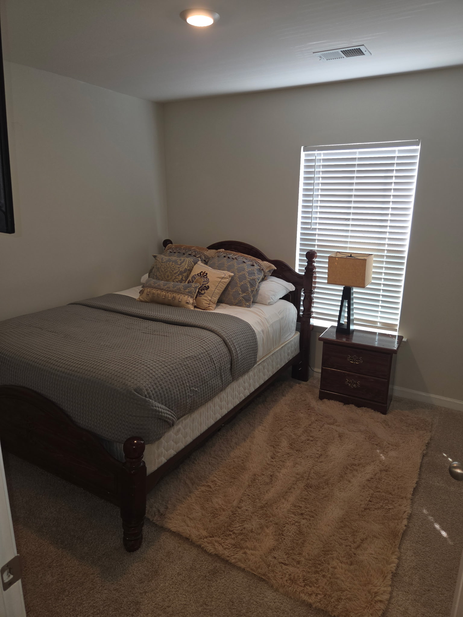 Guest bedroom with a made bed and bedside lamp