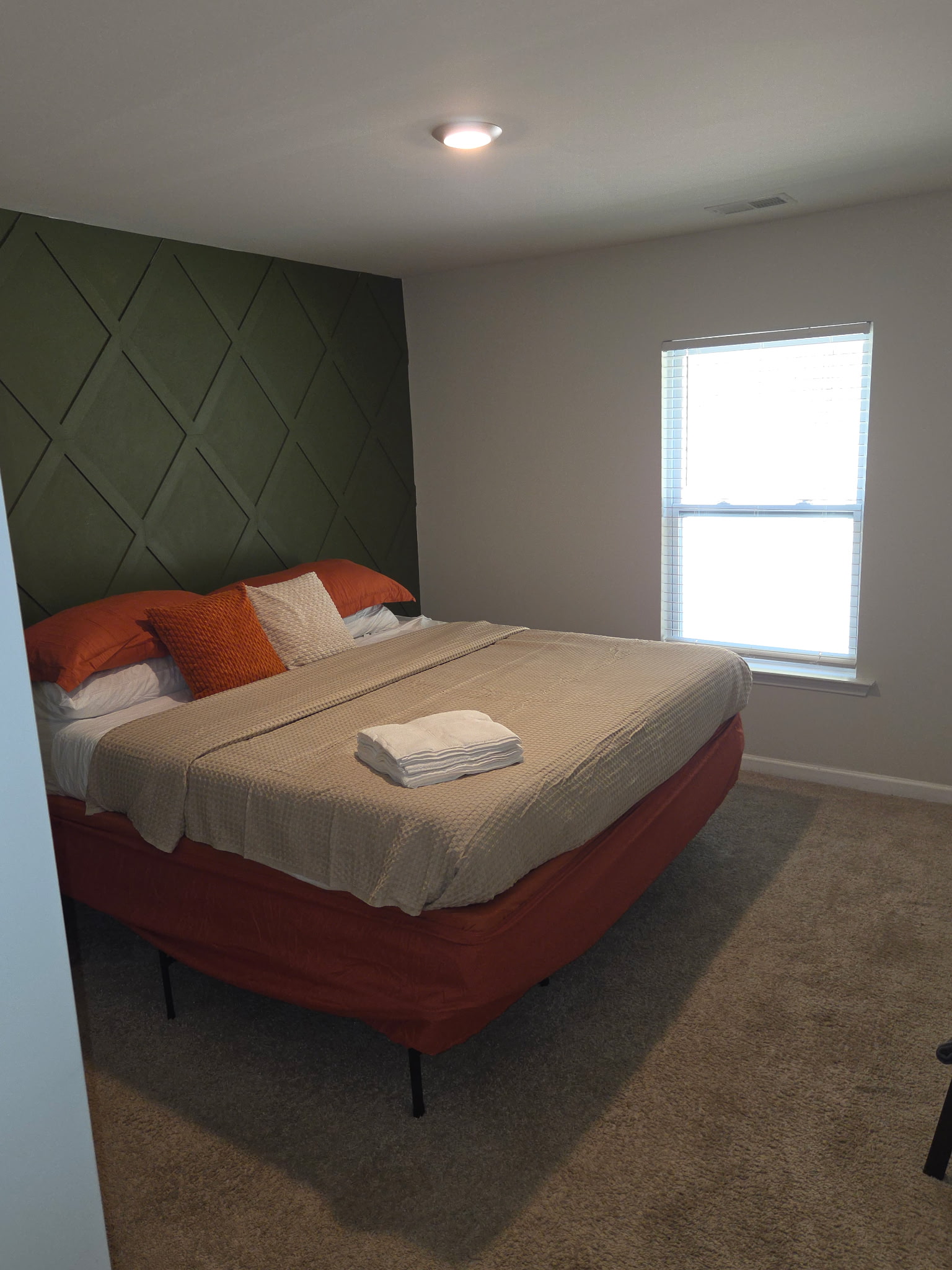 Bedroom with warm accent wall and made bed